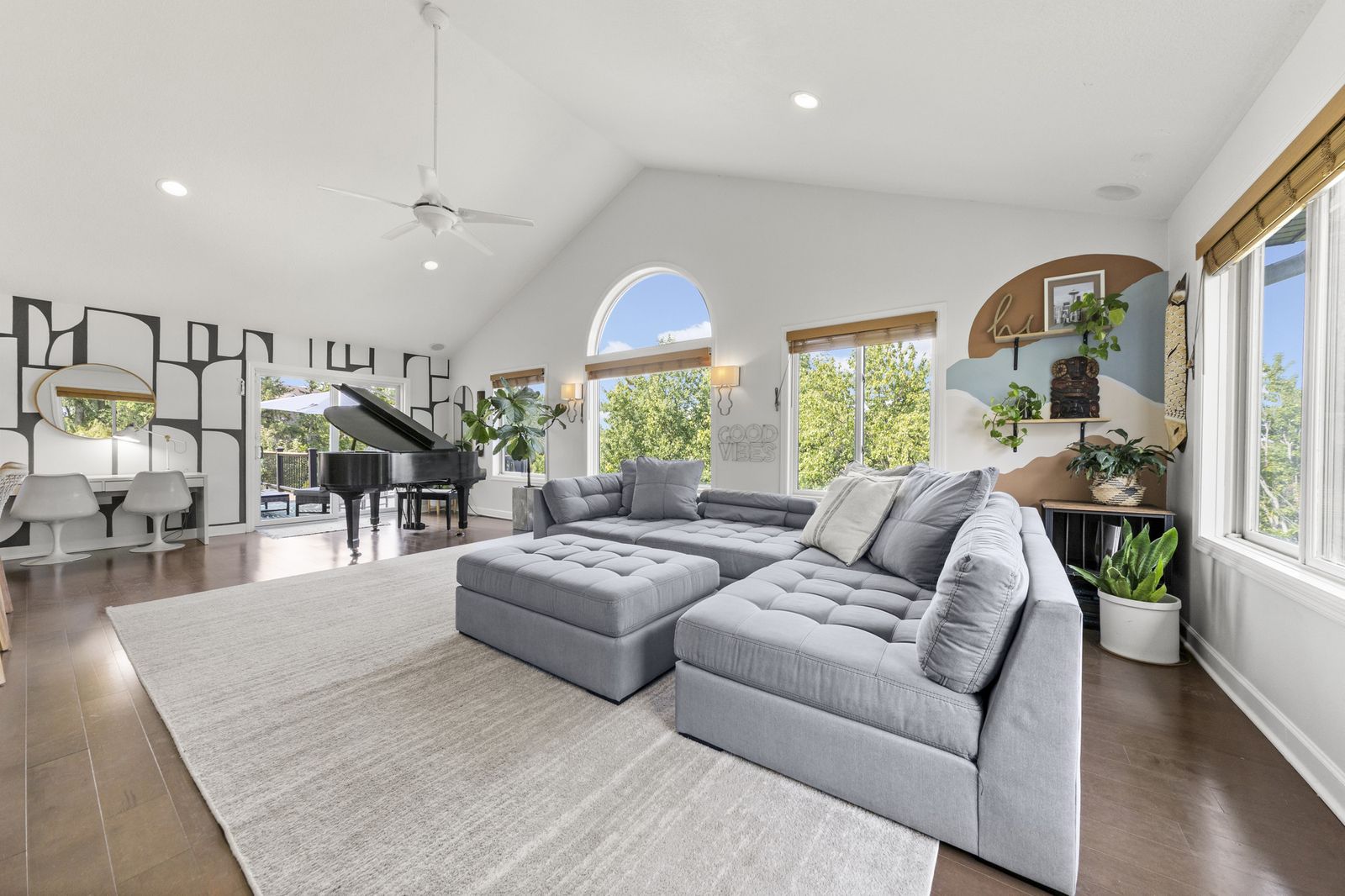 Living room with vaulted ceiling, arched window, and gray sectional