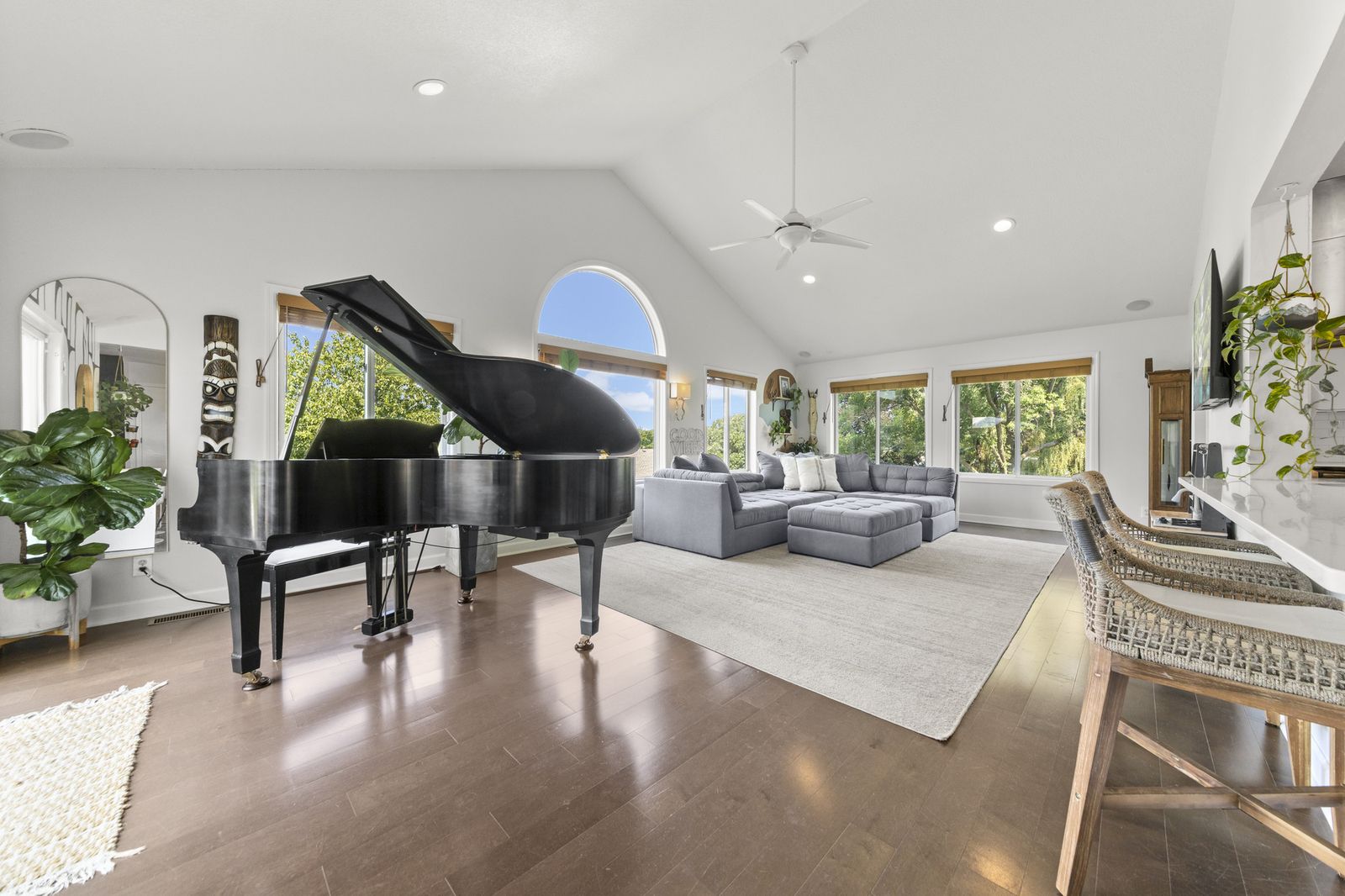 Living room with grand piano and arched window under vaulted ceiling
