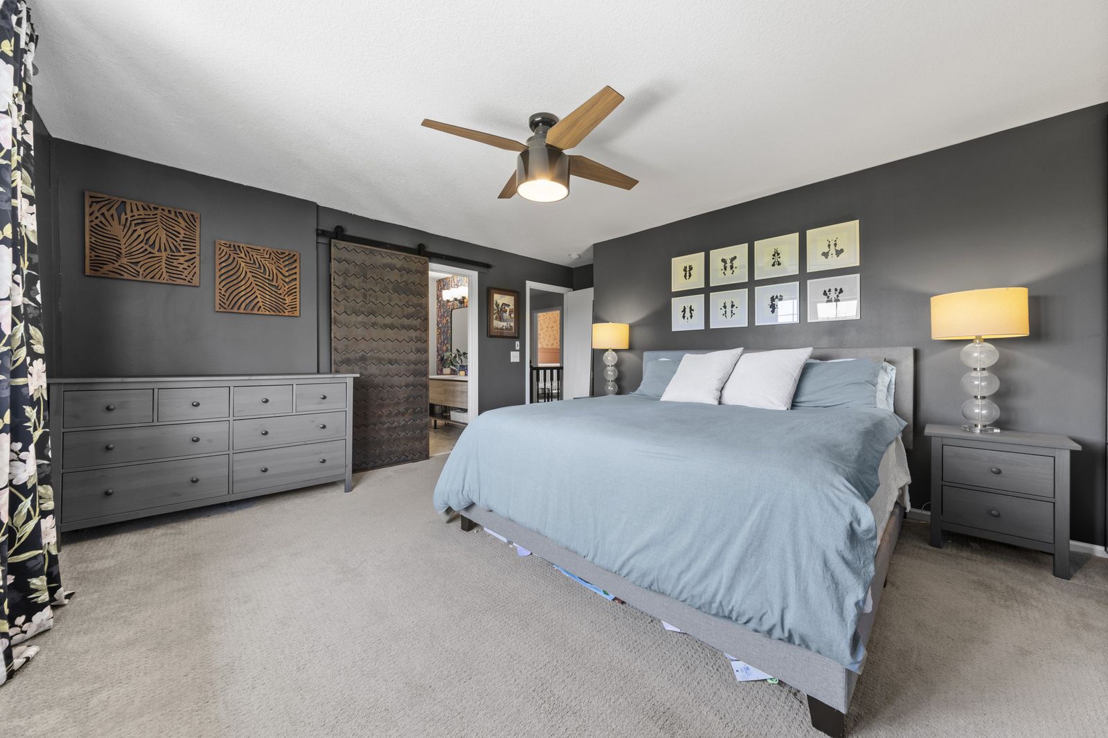 Bedroom with barn door and dresser, dark accent wall