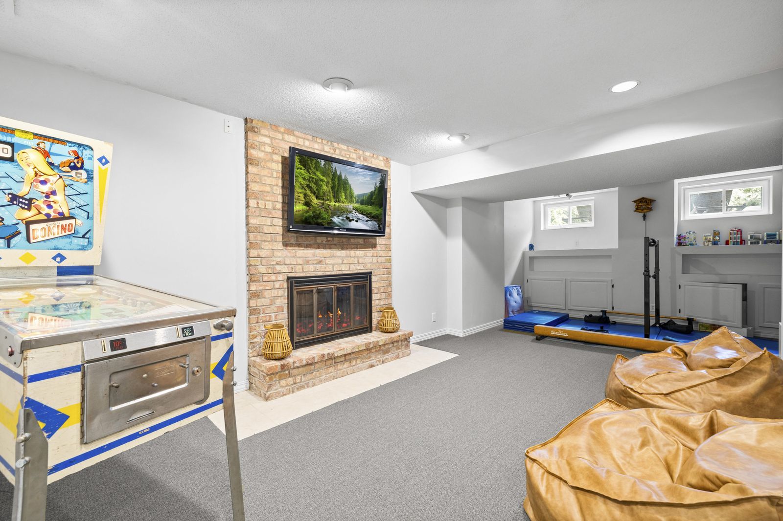 Lower level recreation room with arcade game and fireplace