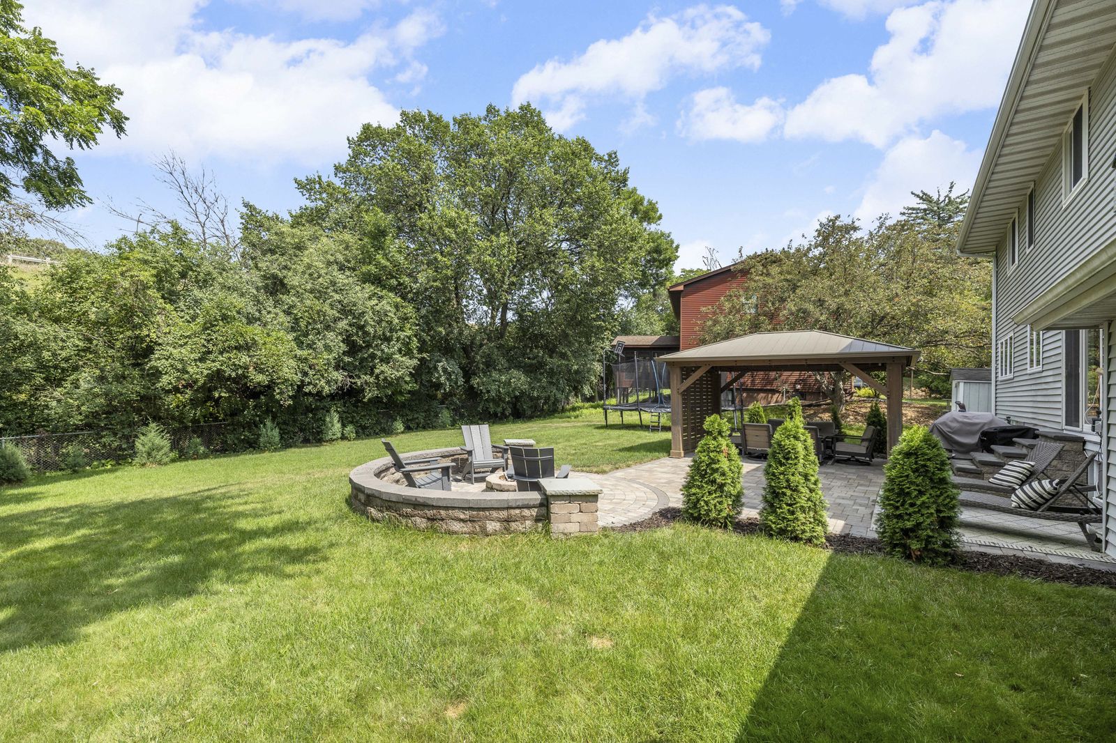 Backyard lawn with fire pit and gazebo in distance