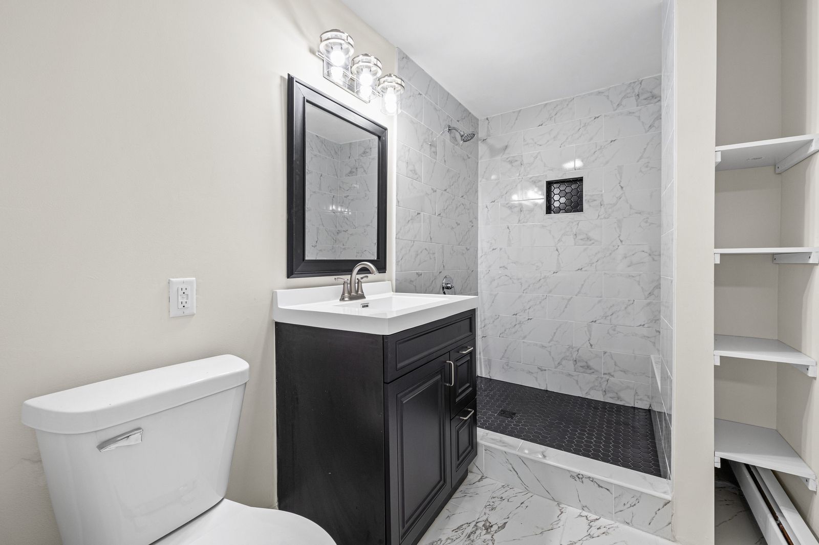 Bathroom with marble tile shower and dark vanity